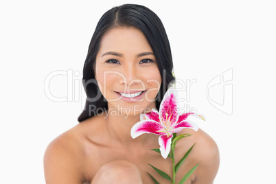 Smiling natural black haired model posing with lily