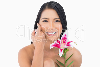Smiling natural model posing with lily and caressing her face