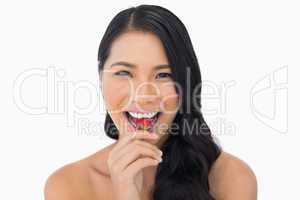 Smiling attractive brown haired model eating strawberry