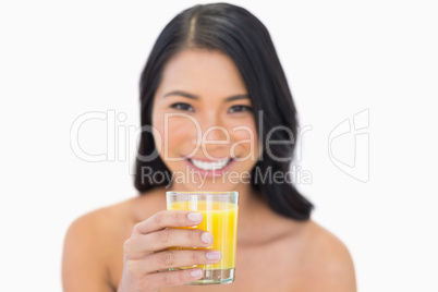 Smiling sensual nude model drinking orange juice