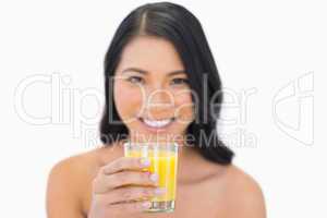 Smiling sensual nude model drinking orange juice