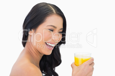 Happy sensual nude model with glass of orange juice