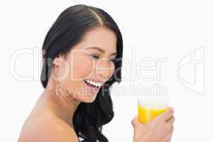 Happy sensual nude model with glass of orange juice