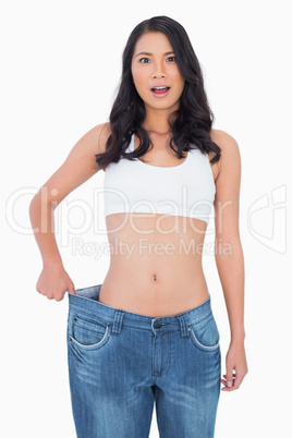 Surprised sexy woman wearing too big jeans