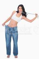 Woman wearing too big pants and strangling herself with measurin
