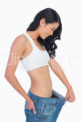 Cheerful woman holding her too big jeans