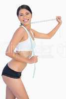 Smiling slim woman playing with her measuring tape