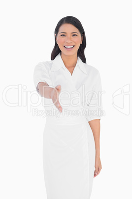 Smiling dark haired model with classy dress holding out her hand