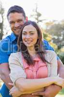 Attractive couple smiling at the camera and hugging