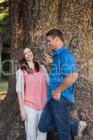 Smiling couple leaning on a tree