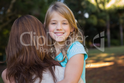 Little girl smiling at camera held by her mother