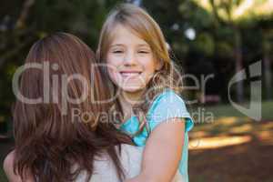 Little girl smiling at camera held by her mother