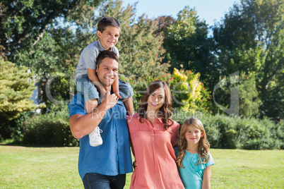 Cute family smiling at camera in the park