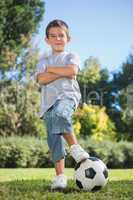 Young boy posing with football with arms crossed