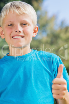 Little blonde boy smiling at camera giving thumbs up