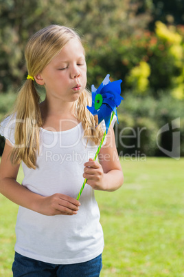 Young blonde girl blowing pinwheel