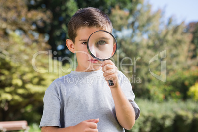 Cute boy looking through a magnifying glass