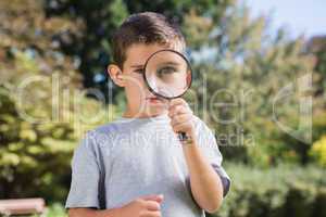 Cute boy looking through a magnifying glass