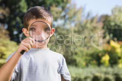 Cheerful boy looking through a magnifying glass