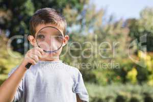 Cheerful boy looking through a magnifying glass