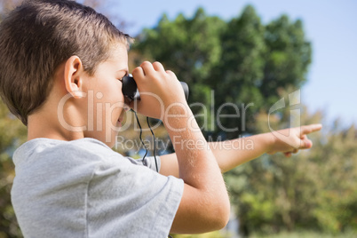 Boy looking through binoculars and pointing