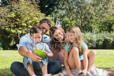 Happy family in a park with father and son inspecting leaf with