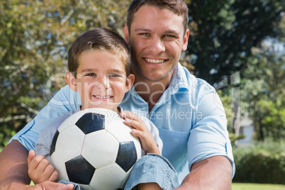 Happy dad and son with a football in a park