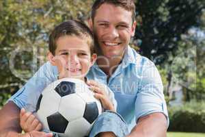 Happy dad and son with a football in a park