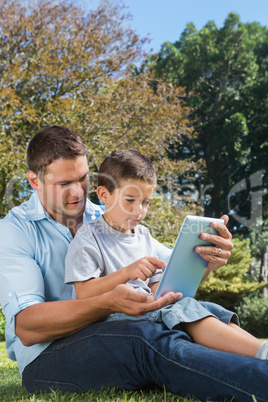 Dad and son playing with a tablet pc in a park