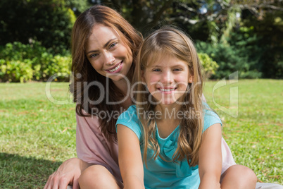 Smiling mother and daughter on the grass