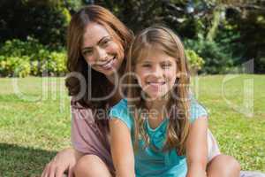 Smiling mother and daughter on the grass