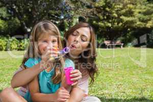 Smiling daughter with mother making bubbles