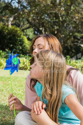 Mother with daughter blowing pinwheel in the park