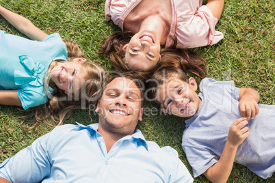 Happy family lying on the grass in a circle