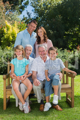 Smiling multi generation family sitting on a bench in park