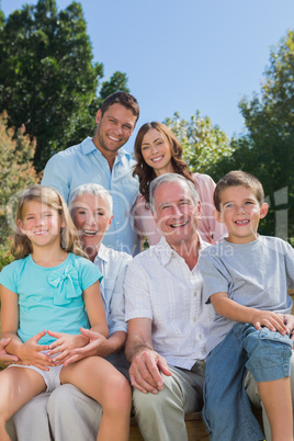 Cheerful multi generation family sitting on a bench in park