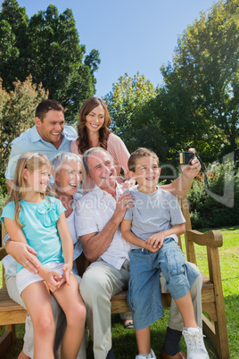 Multi generation family sitting on a bench taking photo of thems