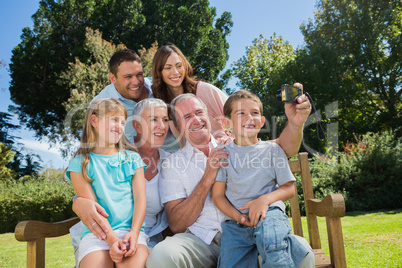 Family sitting on a bench taking photo of themselves