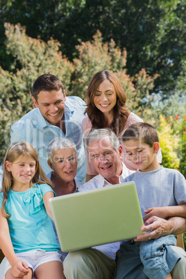 Multi generation family with a laptop sitting in park