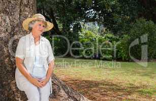 Thoughtful retired woman sitting on tree trunk