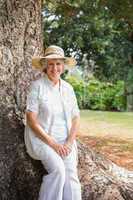 Smiling retired woman sitting on tree trunk