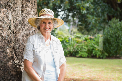 Cheerful retired woman sitting on tree trunk