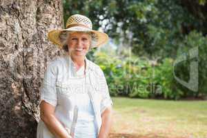 Cheerful retired woman sitting on tree trunk