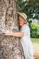 Retired woman hugging a tree and smiling