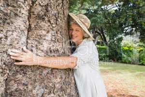 Happy older woman hugging a tree