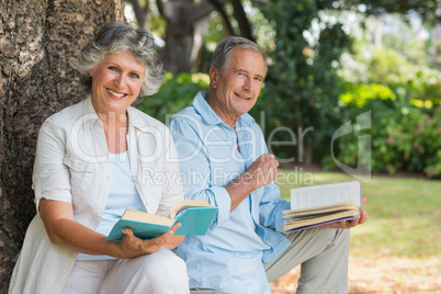 Smiling mature couple reading books together
