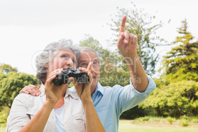Man showing something to his wife holding binoculars