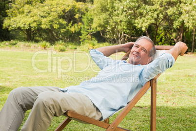 Happy mature man sitting on sun lounger