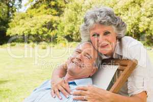 Smiling mature woman standing behind her husband on deck chair