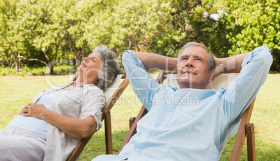 Relaxing mature couple sitting on sun loungers